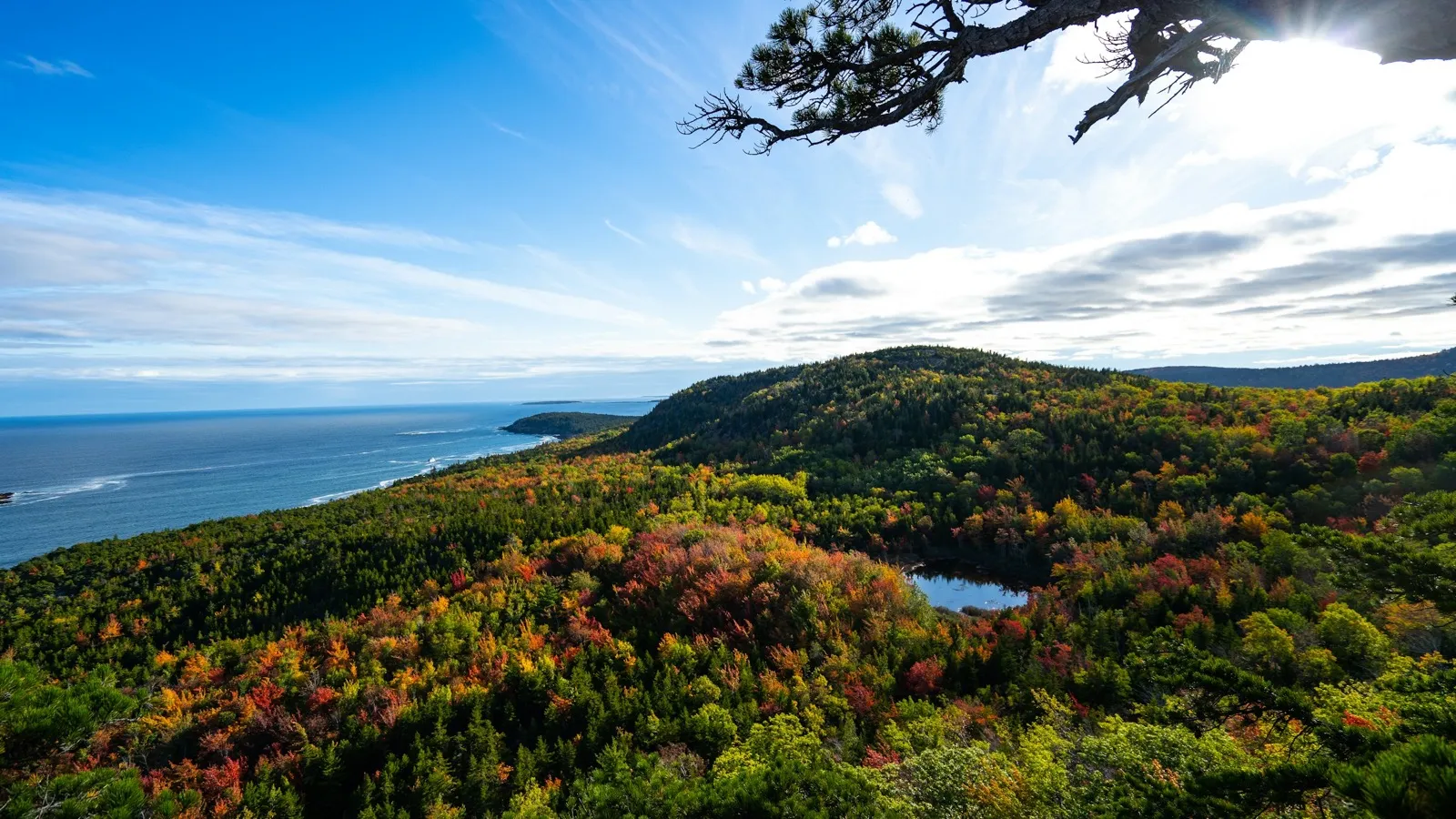 Mountains and lakes in fall color under a blue sky, seen from the air