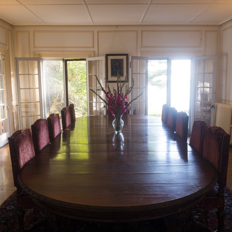 The dining room set for a meal, with tall windows looking out over Frenchman Bay