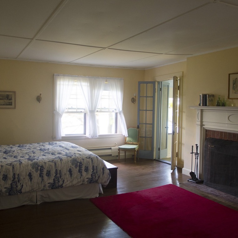 A bedroom with period furnishings and windows open to the sea air